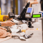 A cashier scans a metal spoon at a store checkout counter.