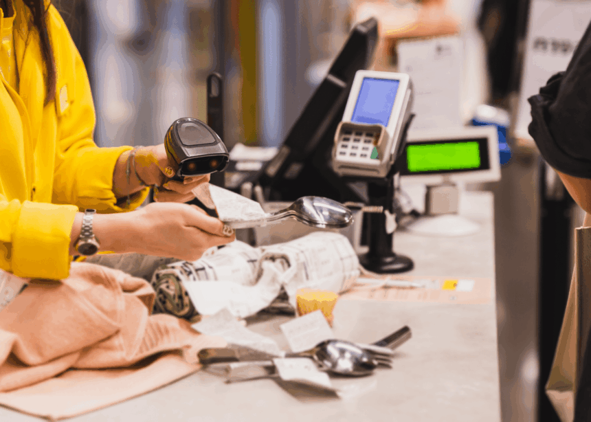 A cashier scans a metal spoon at a store checkout counter.