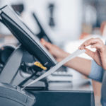 A close-up of a person tearing a receipt from a point-of-sale terminal.