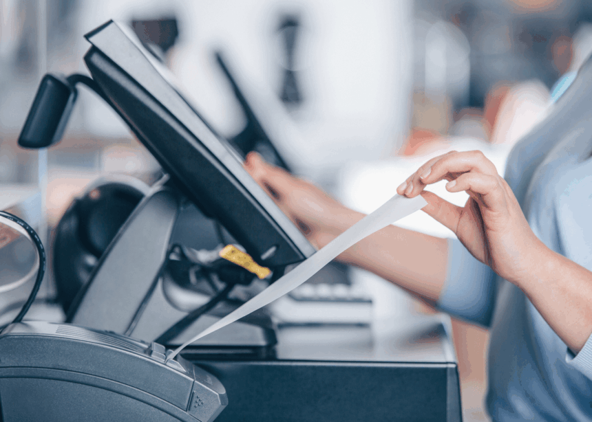 A close-up of a person tearing a receipt from a point-of-sale terminal.