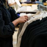 A person browsing through clothes on a rack in a retail store.
