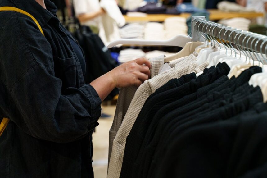 A person browsing through clothes on a rack in a retail store.