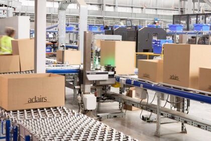 Warehouse staff working with cardboard boxes on automated conveyor belts in a distribution center.