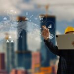 Construction engineer in a hard hat using a tablet with digital overlay icons.