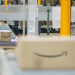 Amazon shipping boxes moving along a conveyor belt in a warehouse.