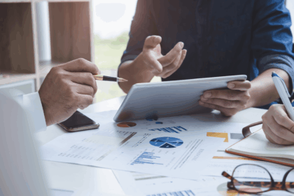 Business professionals discussing financial charts on a tablet during a meeting.