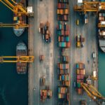 An aerial view of a busy shipping port with cargo ships and stacked containers.