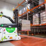 An automated warehouse robot carrying a pallet of Vaalia yogurt products in a storage facility.