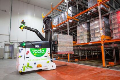 An automated warehouse robot carrying a pallet of Vaalia yogurt products in a storage facility.