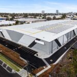 Aerial view of a large modern industrial warehouse building with solar panels.