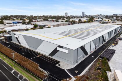 Aerial view of a large modern industrial warehouse building with solar panels.
