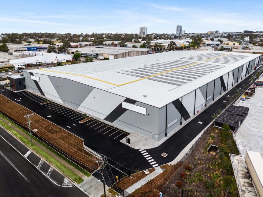 Aerial view of a large modern industrial warehouse building with solar panels.