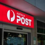 Illuminated Australia Post sign above the entrance to a post office branch.