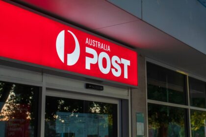 Illuminated Australia Post sign above the entrance to a post office branch.