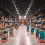 Autonomous robots transport shelves through aisles of a large, well-stocked modern warehouse.