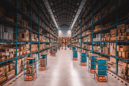Autonomous robots transport shelves through aisles of a large, well-stocked modern warehouse.