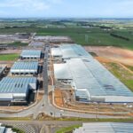 Aerial view of large industrial warehouse complex under construction in a rural landscape.