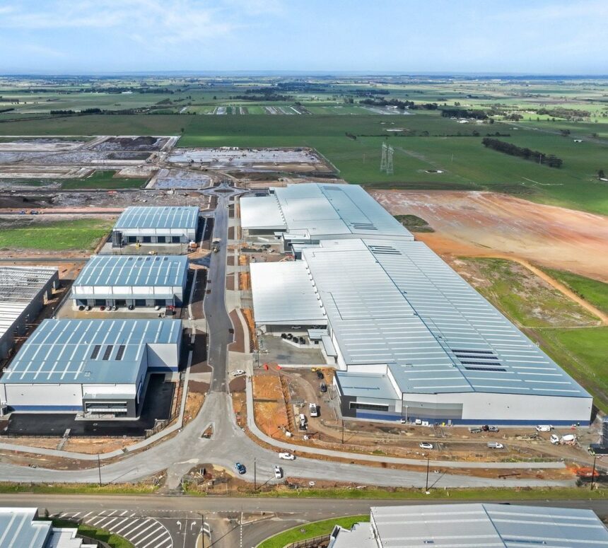 Aerial view of large industrial warehouse complex under construction in a rural landscape.