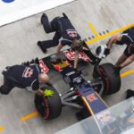 Red Bull pit crew members changing tires on a Formula One race car.