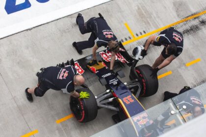 Red Bull pit crew members changing tires on a Formula One race car.