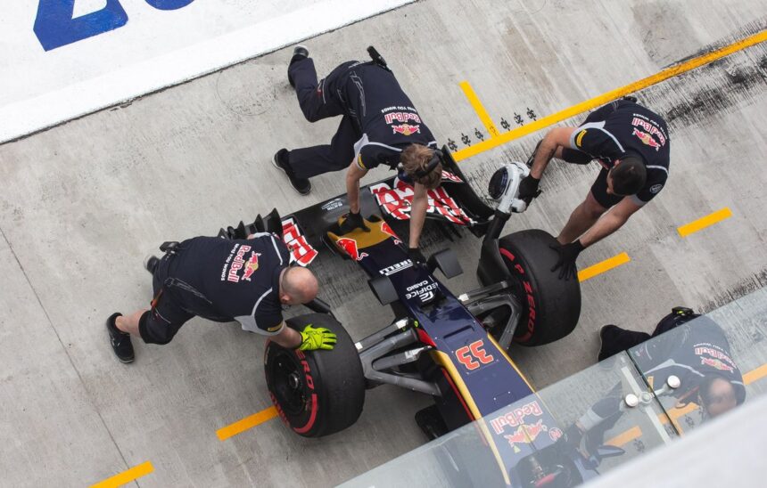 Red Bull pit crew members changing tires on a Formula One race car.
