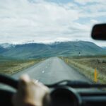 View from inside a car driving towards snow-capped mountains on a remote road.