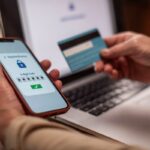 A person uses a smartphone for 2-step verification while holding a credit card.
