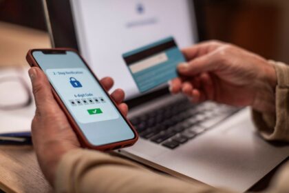 A person uses a smartphone for 2-step verification while holding a credit card.