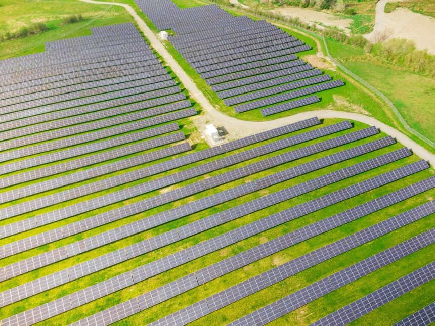Aerial view of a large solar panel farm set in a grassy field.