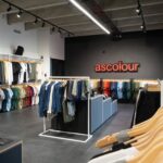 Interior of an AS Colour retail store with clothing racks and industrial design.