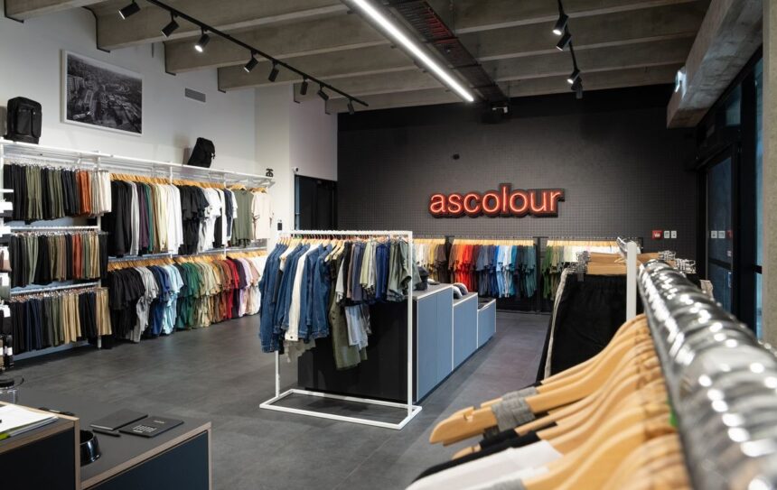 Interior of an AS Colour retail store with clothing racks and industrial design.