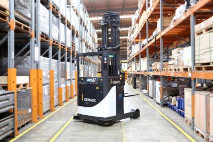 A Dematic automated forklift operating in a large, high-bay warehouse.