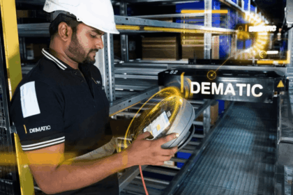 Worker in a hard hat inspects warehouse technology with digital data overlays.