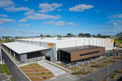 An aerial view of a large, modern DHL Health Logistics warehouse under a blue sky.