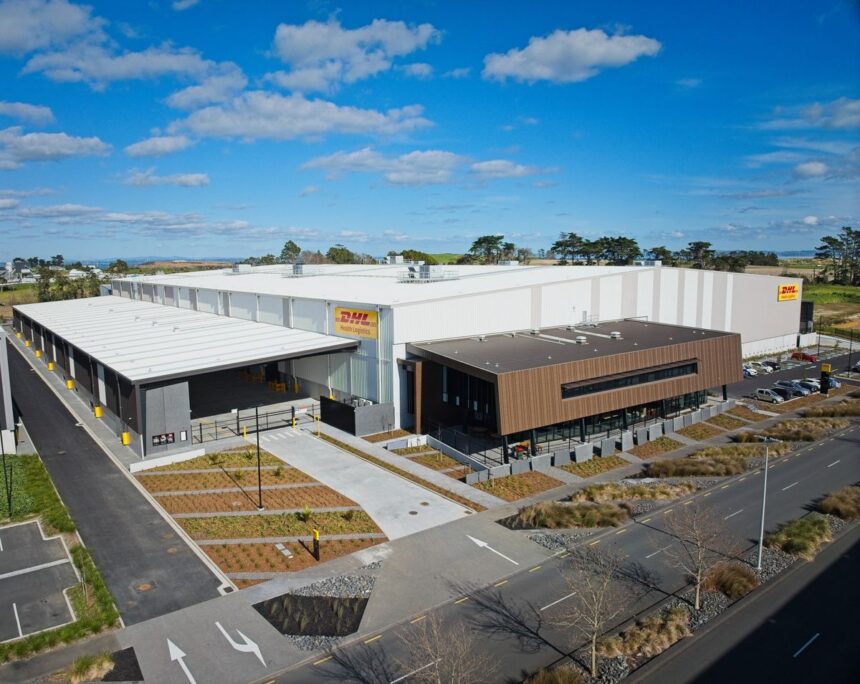 An aerial view of a large, modern DHL Health Logistics warehouse under a blue sky.