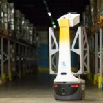 A DHL Locus Robotics autonomous mobile robot moves through a warehouse aisle.