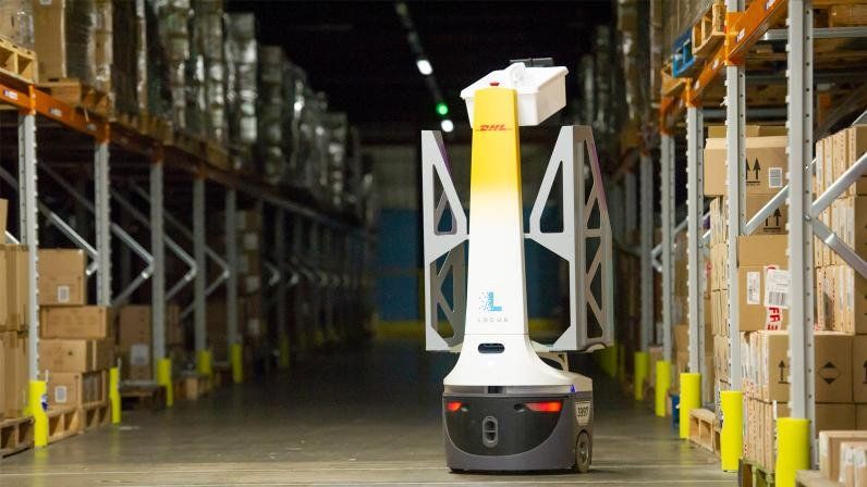 A DHL Locus Robotics autonomous mobile robot moves through a warehouse aisle.