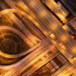 Aerial view of a complex highway interchange illuminated at night with warm golden lights.