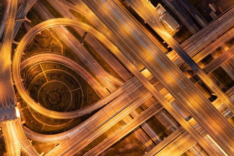 Aerial view of a complex highway interchange illuminated at night with warm golden lights.