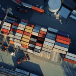 Aerial view of a busy shipping yard with organized rows of stacked cargo containers.