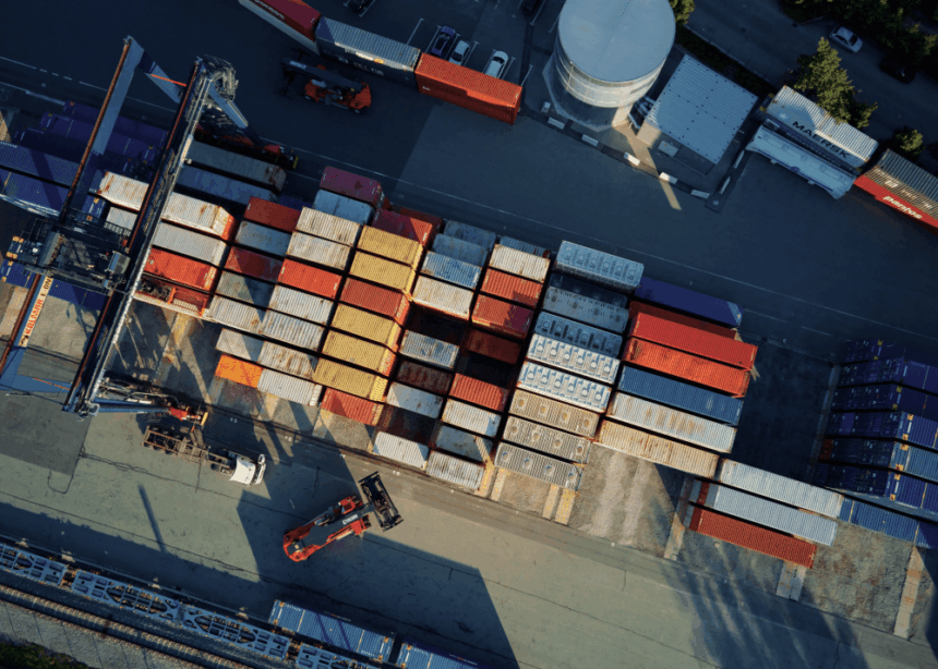 Aerial view of a busy shipping yard with organized rows of stacked cargo containers.