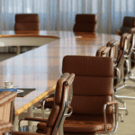 An empty conference room with a long wooden table and leather executive chairs.