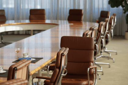 An empty conference room with a long wooden table and leather executive chairs.