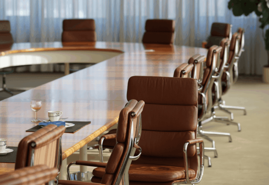 An empty conference room with a long wooden table and leather executive chairs.