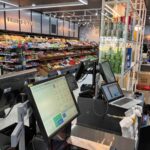Checkout counter with computer terminals in a well-lit grocery store.