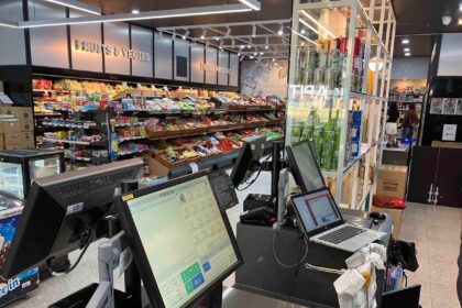 Checkout counter with computer terminals in a well-lit grocery store.