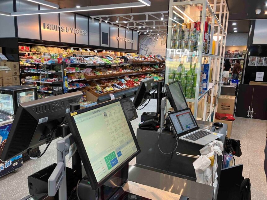 Checkout counter with computer terminals in a well-lit grocery store.