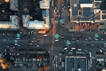 Aerial view of a city intersection with digital map pins overlaid on traffic.