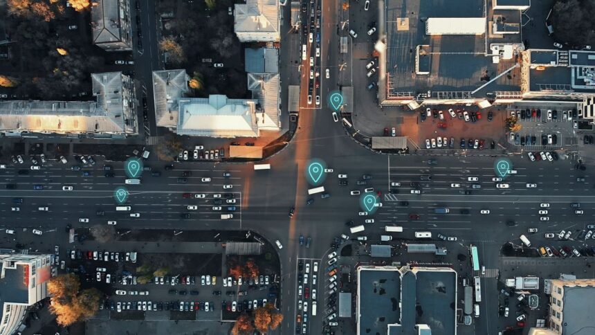 Aerial view of a city intersection with digital map pins overlaid on traffic.