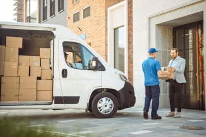 A delivery worker hands a package to a customer outside a modern building.